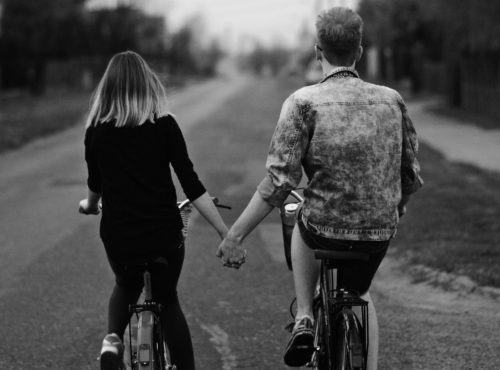 B/w image of couple riding bicycles side by side and holding hands