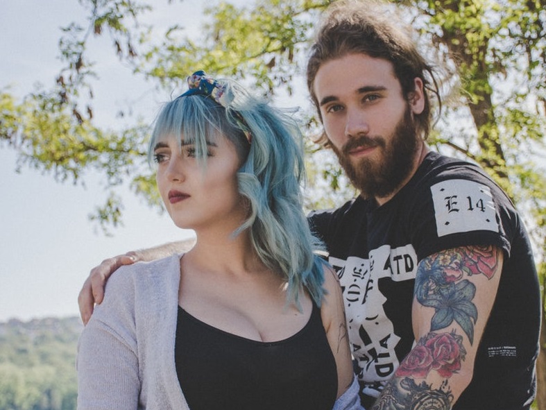 Young caucasian couple with tattoos and blue hair.