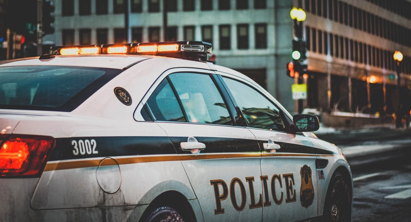 Police car with orange lights at city intersection