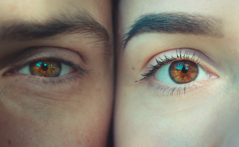 closeup of a man and woman's face pressed together with just one eye showing on each face