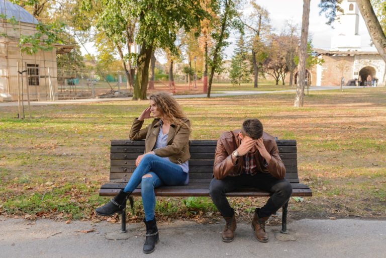 Couple sitting on park bench after an argument.
