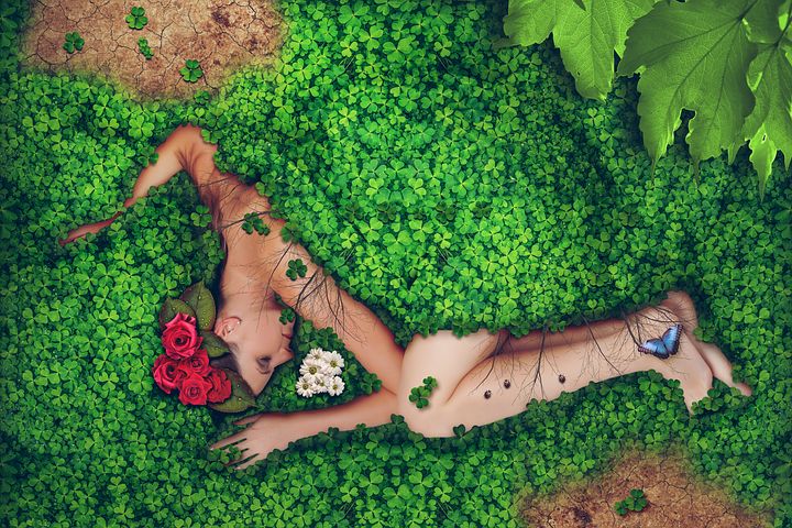 A naked woman asleep with roses in her hair half-covered with clover in a fetal position